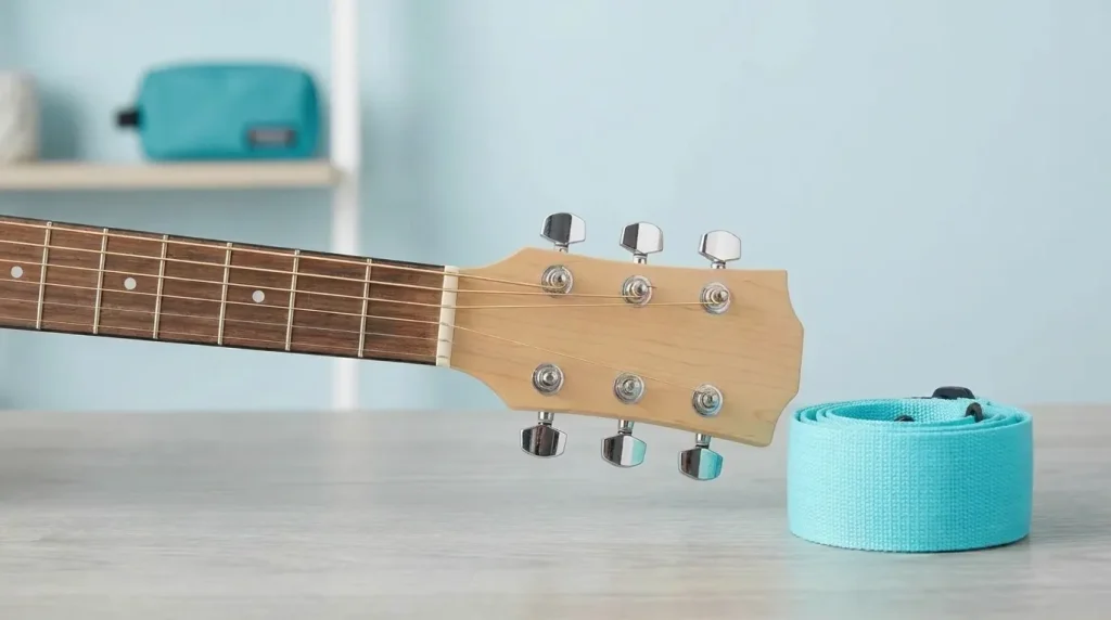 Best Beginner Guitar: Close-up of a beginner acoustic guitar's headstock and fretboard with a turquoise strap